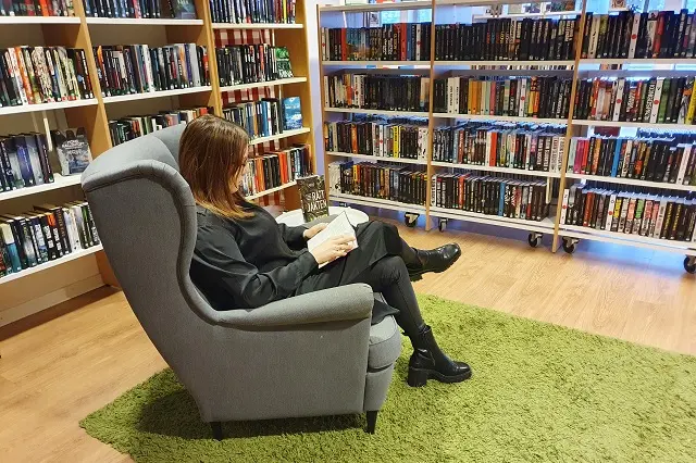Kvinna sitter i fåtölj och läser